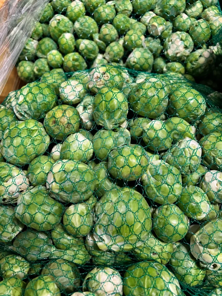 Świeża brukselka w zielonych siatkach w skrzynce w hurtowni Quali Fruits